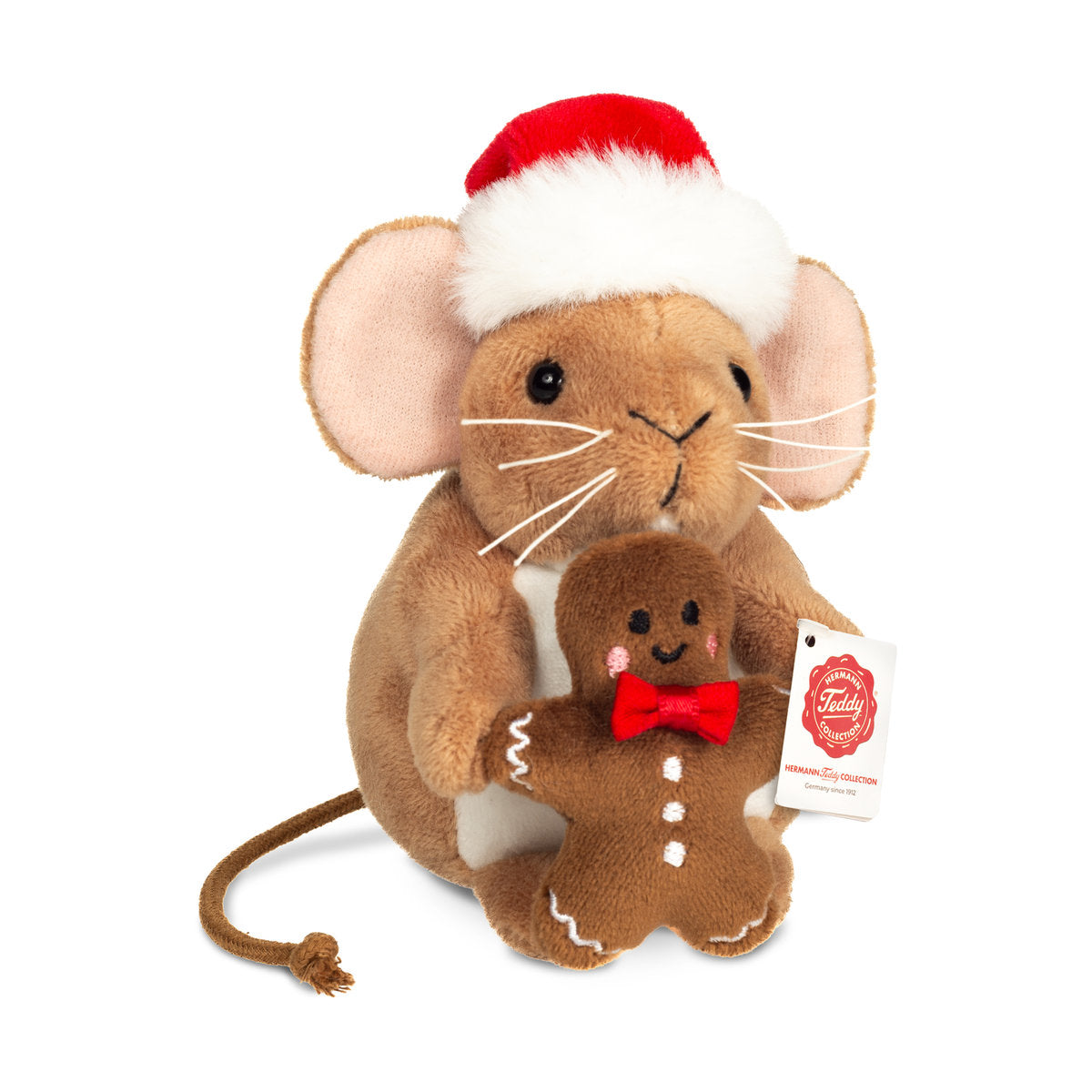 Det här är en julmus från Teddy-Hermann. Liten sittande mus med kort, slät brun päls, vit fläck på magen och lång tunn svans med knut i änden. Nosen är brun, öronens insida ljust rosa och tassarna bruna. Ögonen är svarta och runda, nosspetsen liten och svart, och vita trådmorrhår sticker ut. Musen håller en brun pepparkaksgubbe med vit glasyr, rosa kinder och liten röd fluga, och bär en röd tomteluva med vit kant och tofs. Uttrycket är milt och nyfiket.