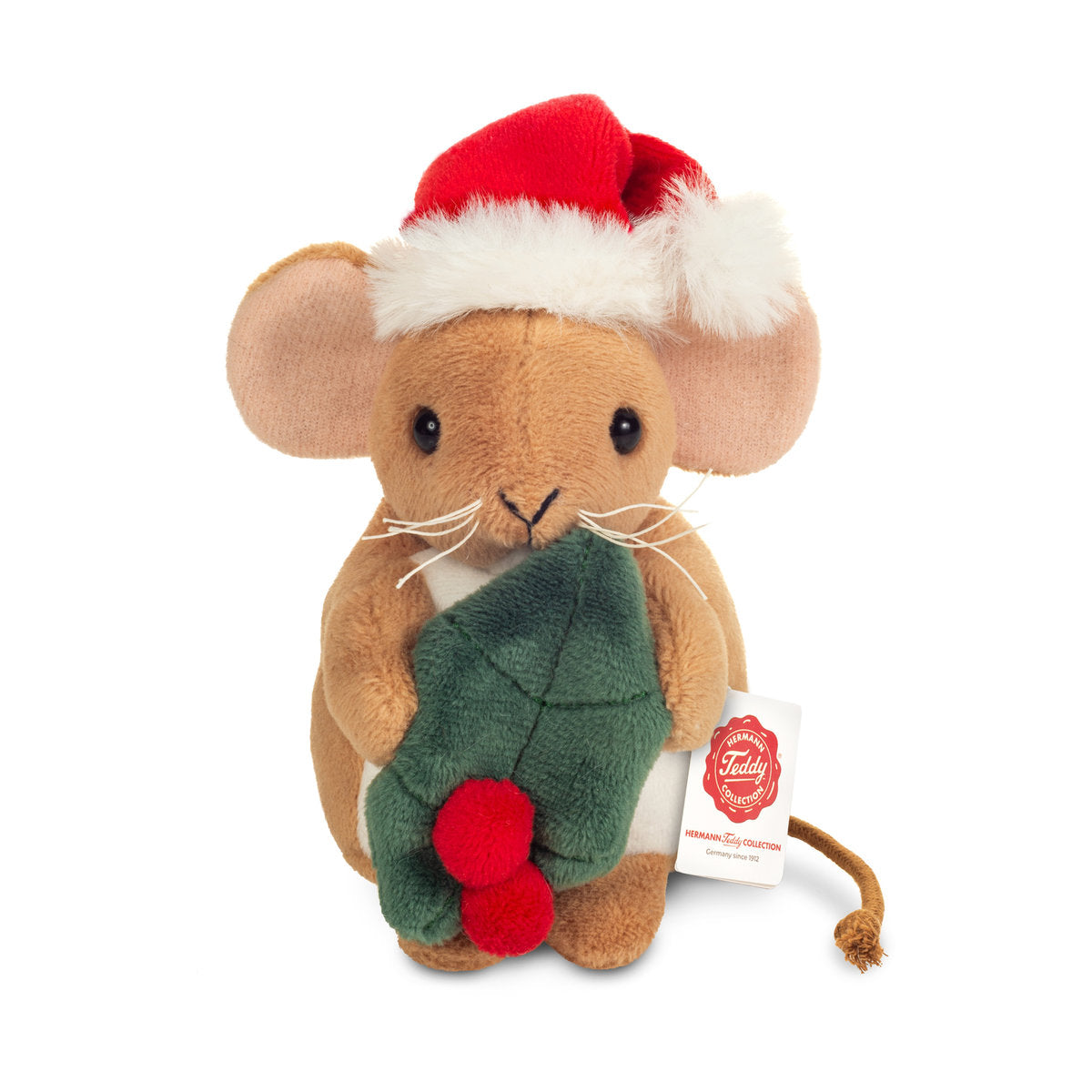 Tämä on Teddy-Hermannin pieni jouluhiiri. Hänellä on lyhyt, sileä beige turkki ja valkoinen masu, ja korvien sisäpuolet ovat vaaleanpunaiset. Silmät ovat mustat ja pyöreät, nenä pieni ja musta, ja kuonon molemmin puolin on valkoiset viikset. Selästä lähtee ohut ruskea nyörihäntä. Hiiri istuu ryhdikkäästi ja pitelee vihreää piikkipaatsamanlehteä, jossa on kaksi punaista marjaa. Päässä on punainen tonttulakki, jossa on valkoinen pehmoreunus ja tupsu. Ilme on lempeä ja tyytyväinen.