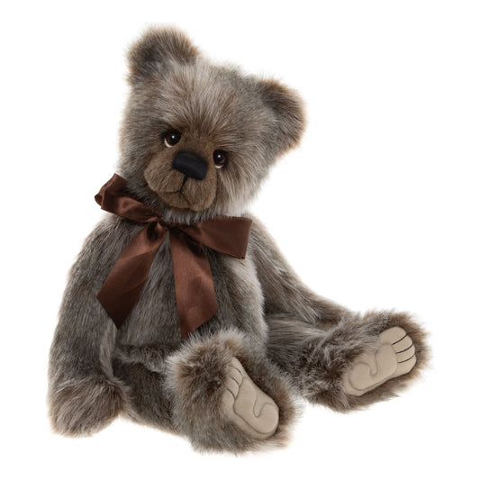 This is Ollie by Charlie Bears. Sitting bear with long, soft-looking fur that is predominantly gray with noticeable brown shading and small areas of white; the fur appears straight, medium-long and has a slight sheen. Muzzle is brown and slightly darker than the surrounding fur; inner ears are gray with brown edges; tummy and the visible outer paws match the gray-brown fur; paw pads are beige. Eyes are dark brown and glossy with small white painted eye crescents beneath them. Nose is black and rectangu...
