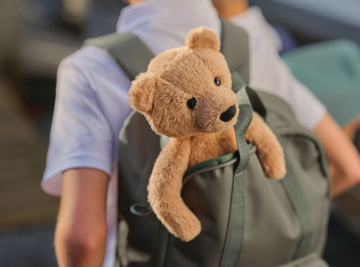 Charlie Bear peeking out of a backpack