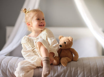 Girl smiling with Charlie Bear on the bed