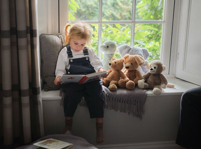 Child reading by the window with Bear & Me friends